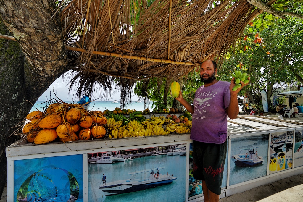 Ob frisch gefangener Fisch oder frisches Obst, Einheimische bieten ihre Produkte direkt am Straßenrand an. Im Bild ist Randy zu sehen, unser Lieblings “take-awayer” am Strand von Beau Vallon. Bei ihm ist täglich frisches Obst garantiert