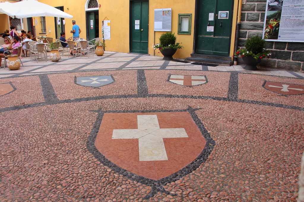 Stolz prangt das Wappen der kleinsten Seerepublik Italiens als Mosaik im Straßenpflaster der Altstadt Nolis
