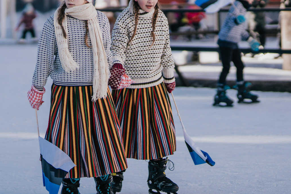 Kleine Eisläuferinnen vor dem Rathaus in Tartu, Estlands Flagge inklusive